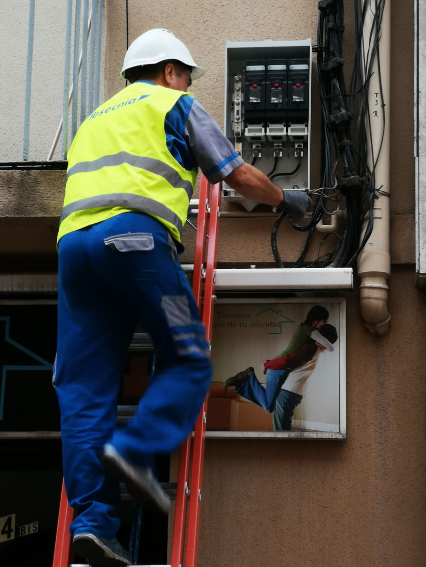 electricista arreglant quadre de llums en una façana